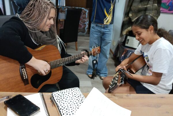 Madi Colville-Walker and Fatai Morgan playing guitars during a songwriting workshop