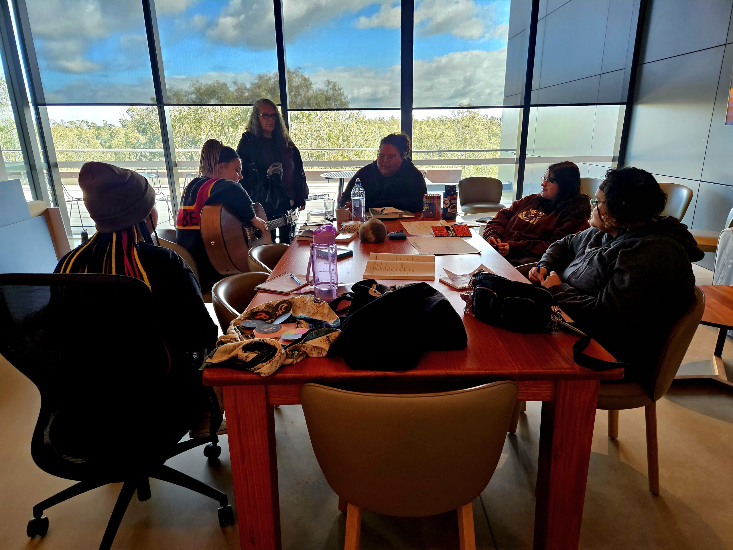 Community members taking part in a songwriting workshop around a table