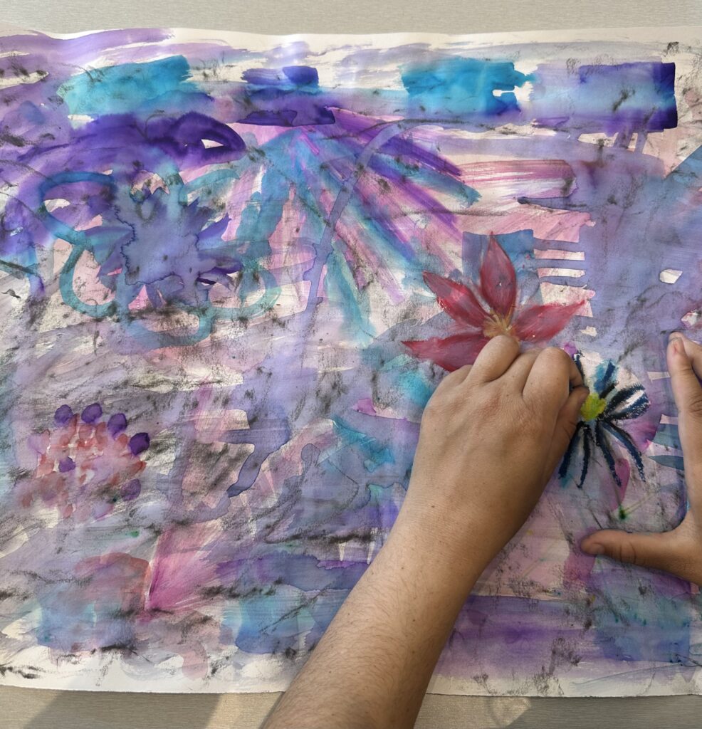 A young person painting a floral artwork in the Kaiela Arts studio