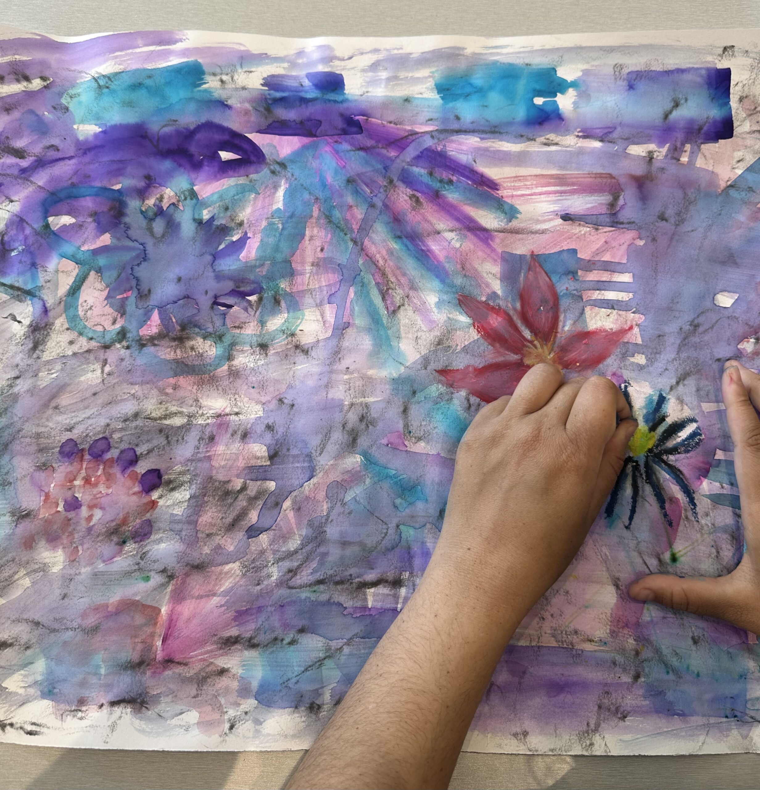 A young person painting a floral artwork in the Kaiela Arts studio